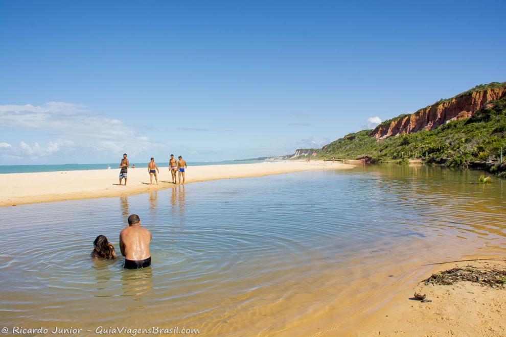 Imagem de pessoas curtindo a piscina natural na Praia de Pitinga.